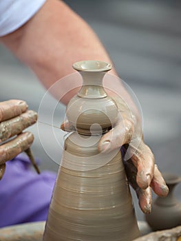 Hands making pottery on a wheel