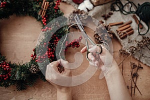 Hands making rustic christmas wreath, cutting rope with scissor