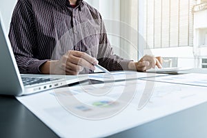 The hands of a male businessman are analyzing and calculating the annual income and expenses in a financial graph that shows