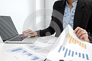 The hands of a male businesswoman are analyzing and calculating the annual income and expenses in a financial graph that shows