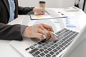 The hands of a male businesswoman are analyzing and calculating the annual income and expenses in a financial graph that shows