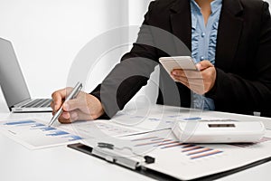 The hands of a male businesswoman are analyzing and calculating the annual income and expenses in a financial graph that shows