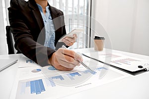 The hands of a male businesswoman are analyzing and calculating the annual income and expenses in a financial graph that shows