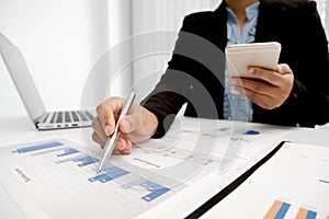 The hands of a male businesswoman are analyzing and calculating the annual income and expenses in a financial graph that shows