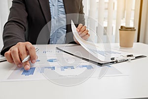 The hands of a male businesswoman are analyzing and calculating the annual income and expenses in a financial graph that shows