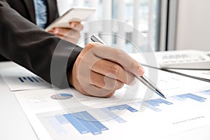 The hands of a male businesswoman are analyzing and calculating the annual income and expenses in a financial graph that shows