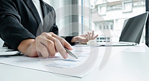 The hands of a male businesswoman are analyzing and calculating the annual income and expenses in a financial graph that shows