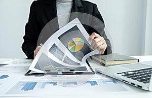 The hands of a male businesswoman are analyzing and calculating the annual income and expenses in a financial graph that shows