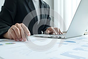 The hands of a male businesswoman are analyzing and calculating the annual income and expenses in a financial graph that shows