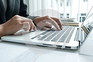 The hands of a male businesswoman are analyzing and calculating the annual income and expenses in a financial graph that shows