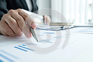 The hands of a male businesswoman are analyzing and calculating the annual income and expenses in a financial graph that shows