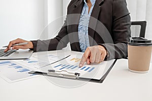 The hands of a male businesswoman are analyzing and calculating the annual income and expenses in a financial graph that shows