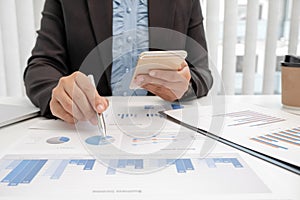 The hands of a male businesswoman are analyzing and calculating the annual income and expenses in a financial graph that shows