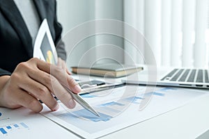 The hands of a male businesswoman are analyzing and calculating the annual income and expenses in a financial graph that shows