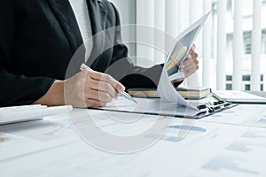 The hands of a male businesswoman are analyzing and calculating the annual income and expenses in a financial graph that shows