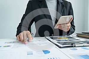 The hands of a male businesswoman are analyzing and calculating the annual income and expenses in a financial graph that shows