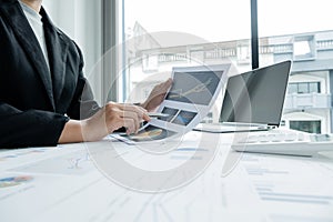 The hands of a male businesswoman are analyzing and calculating the annual income and expenses in a financial graph that shows