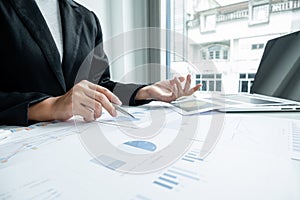 The hands of a male businesswoman are analyzing and calculating the annual income and expenses in a financial graph that shows