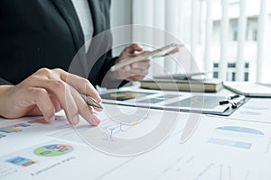 The hands of a male businesswoman are analyzing and calculating the annual income and expenses in a financial graph that shows