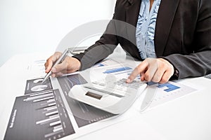 The hands of a male businesswoman use the calculator are analyzing and calculating the annual income and expenses in a financial