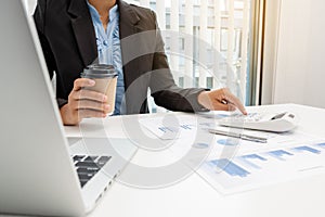 The hands of a male businesswoman use the calculator are analyzing and calculating the annual income and expenses in a financial