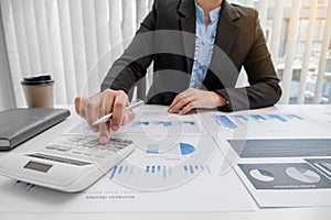 The hands of a male businesswoman use the calculator are analyzing and calculating the annual income and expenses in a financial