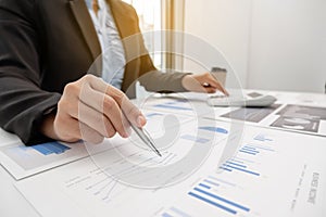 The hands of a male businesswoman use the calculator are analyzing and calculating the annual income and expenses in a financial