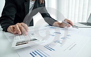 The hands of a male businesswoman use the calculator are analyzing and calculating the annual income and expenses in a financial