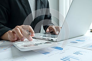 The hands of a male businesswoman use the calculator are analyzing and calculating the annual income and expenses in a financial