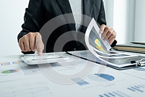 The hands of a male businesswoman use the calculator are analyzing and calculating the annual income and expenses in a financial