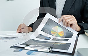 The hands of a male businesswoman use the calculator are analyzing and calculating the annual income and expenses in a financial