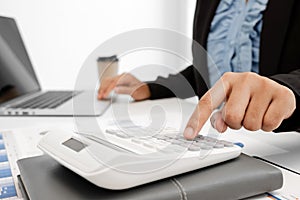 The hands of a male businesswoman use the calculator are analyzing and calculating the annual income and expenses in a financial