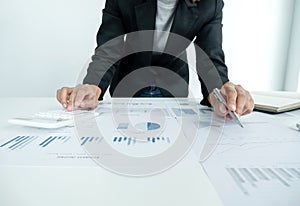 The hands of a male businesswoman use the calculator are analyzing and calculating the annual income and expenses in a financial