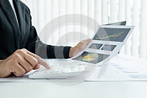 The hands of a male businesswoman use the calculator are analyzing and calculating the annual income and expenses in a financial