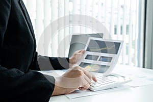 The hands of a male businesswoman use the calculator are analyzing and calculating the annual income and expenses in a financial