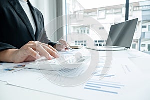 The hands of a male businesswoman use the calculator are analyzing and calculating the annual income and expenses in a financial