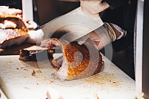 Hands of a Male Chop Roasted Pork with a Meat Cleaver