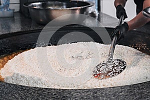 hands of a male cook cooking traditional oriental Uzbek rice pilaf in a cauldron. Central Asian Pilaf Center in