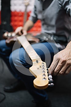 Hands of male guitar player setting tone to electric guitar