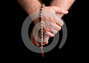 Hands of a male priest with a wooden rosary