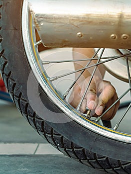 Hands of man check inflator pressure and inflates a tire on motorcycle with an air compressor. Man checking air pressure and