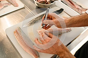 hands of a man chef accurate cleans fish fillets from bones.