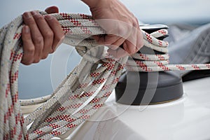 Hands of a man coiling up a rope, the halyard on a sailboat photo