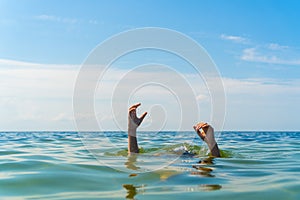 the hands of a man drowning in the sea