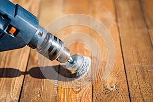 Hands man with electrical rotating brush metal disk sanding a piece of wood