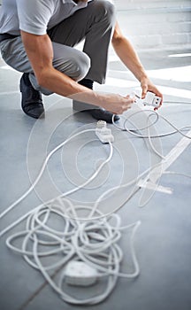 Hands, man and electrician plug connection, power and electricity in office. Cord, wire and cable on floor, socket and