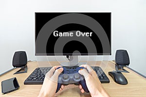 Hands man hold gamepad in front of blank tv screen with game over