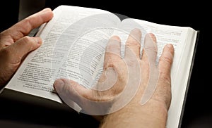 the hands of a man holding the bible while studying it