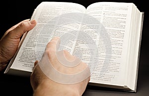 the hands of a man holding the bible while studying it