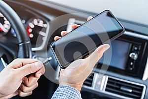 Hands man holding and charging battery mobile smartphone in car with cable in luxury interior car design